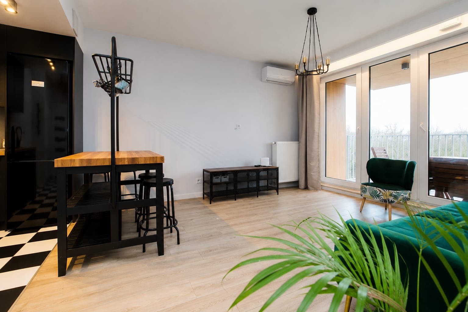Salon z zielonym fotelem i przeszkleniem na balkon, mieszkanie przy Aignera na Ursynowie w Warszawie