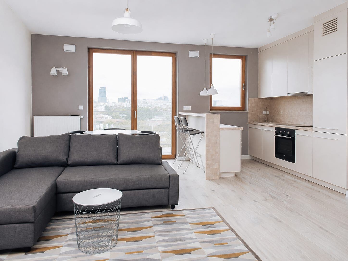 Living room with a charcoal sofa, breakfast bar and city view, apartment in Wola, Warsaw