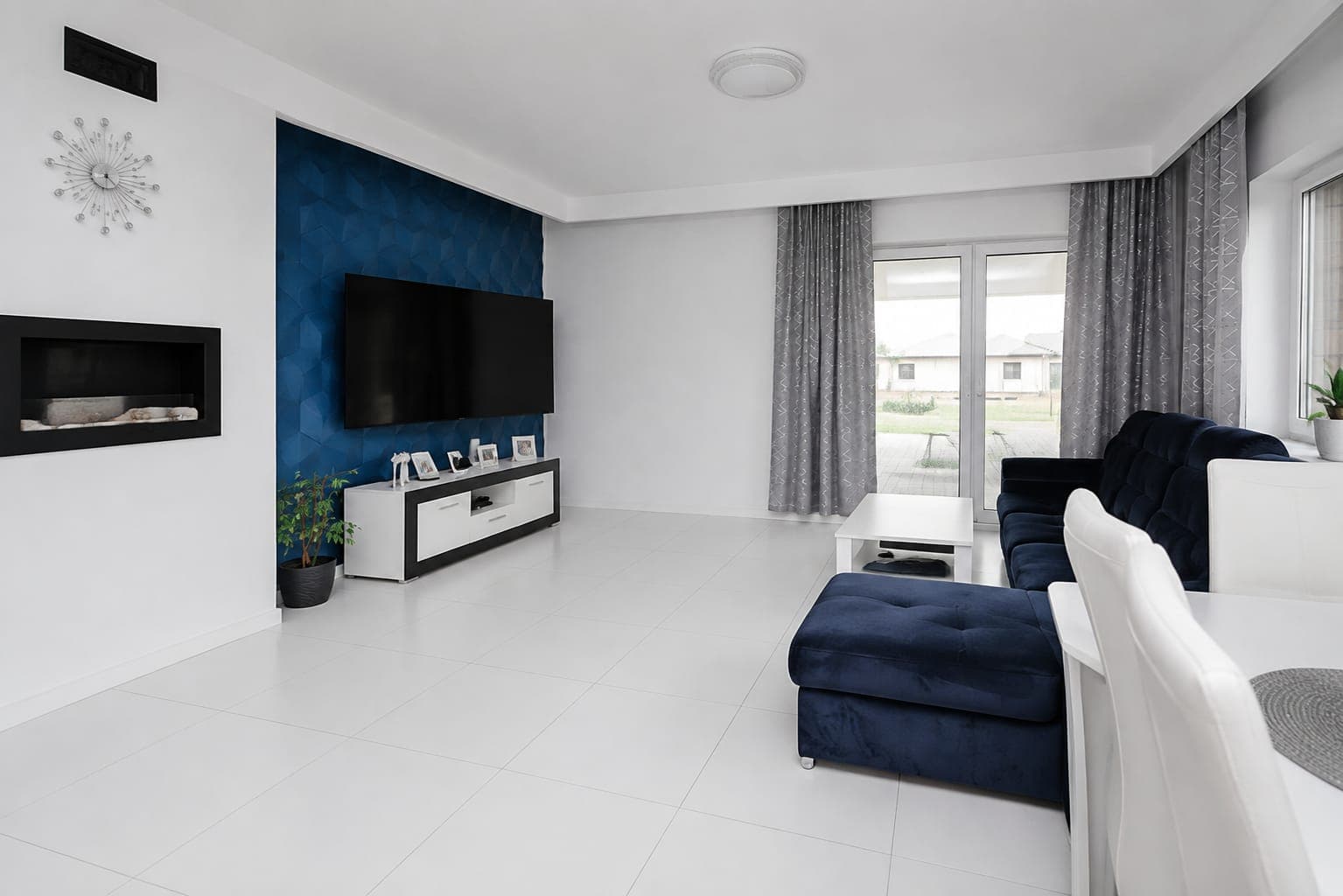 Living room with a navy sofa, fireplace and TV wall, house in Jachranka near Warsaw