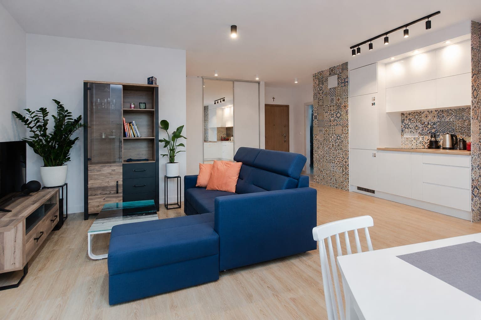 Living room with a navy sofa and a kitchen with patterned tiles, apartment on Sierakowskiego in Praga-Północ, Warsaw