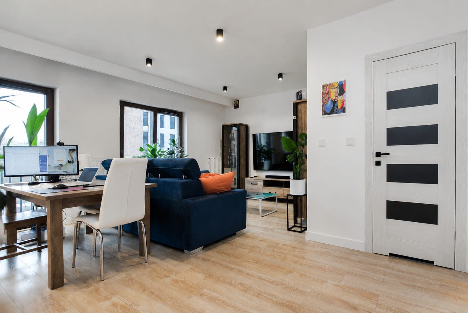 Living room with a desk by the window and a navy sofa, apartment on Sierakowskiego in Praga-Północ, Warsaw